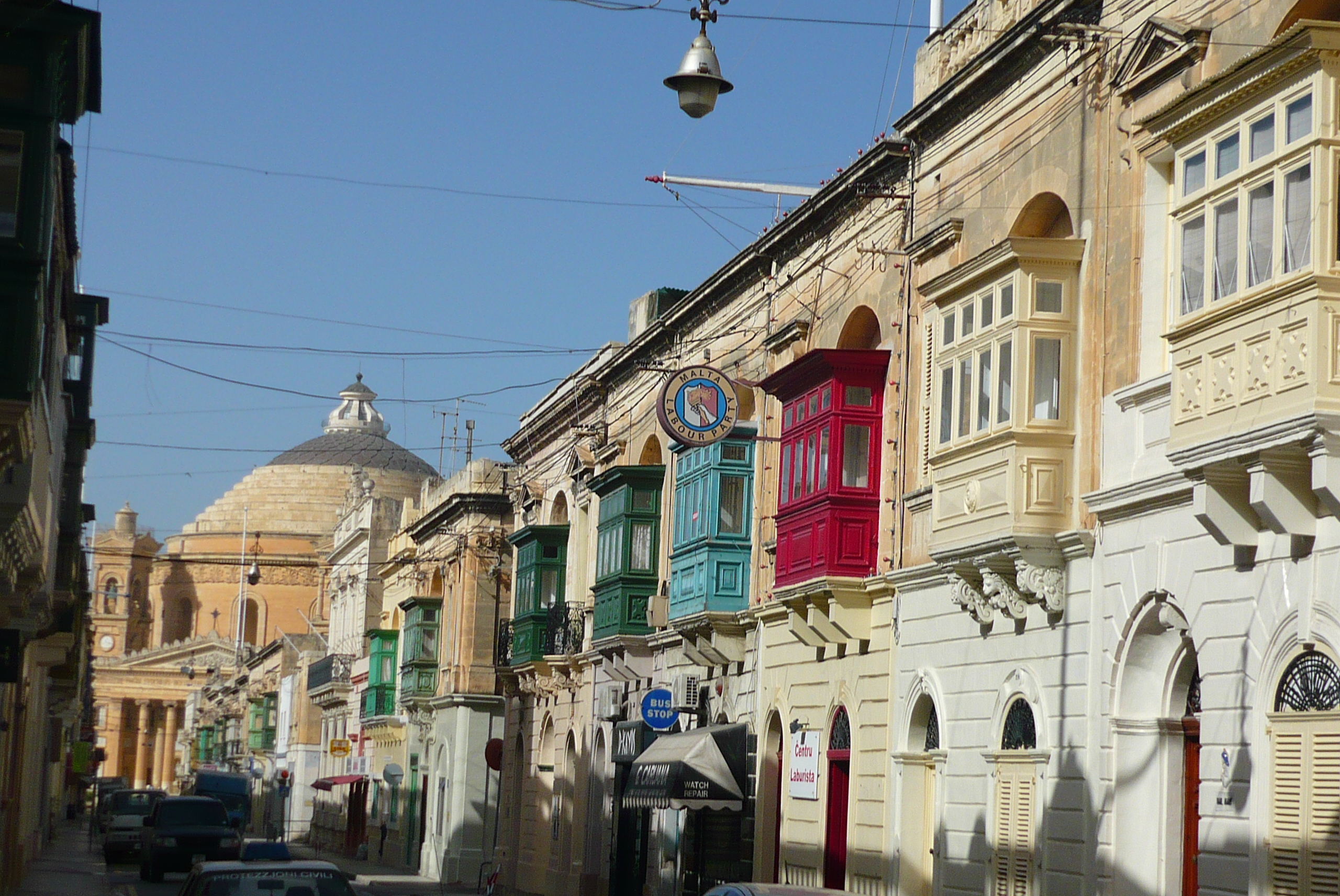 Strasse_in_Mosta_mit_typischen_maltesischen_Balkonen_und_der_Kirche_mit_der_Rotunda